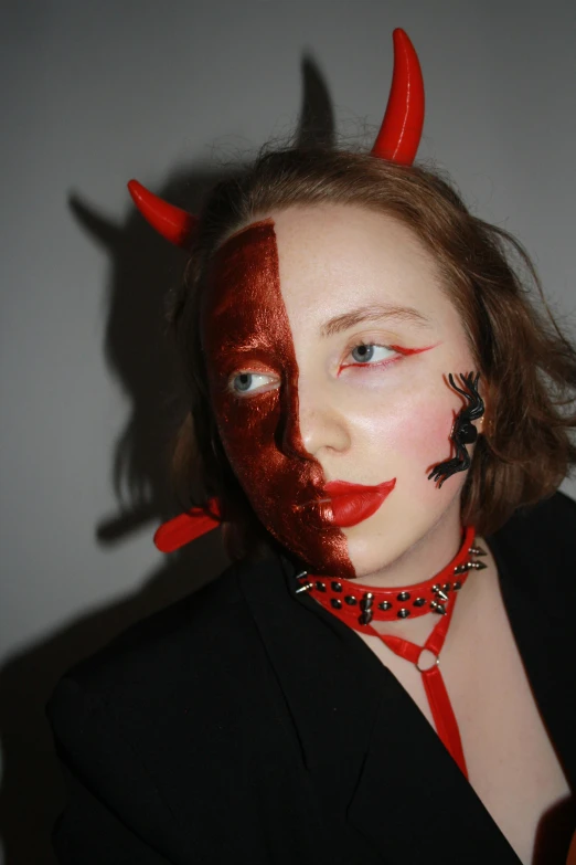 a woman is dressed as a devil with red horns and nails