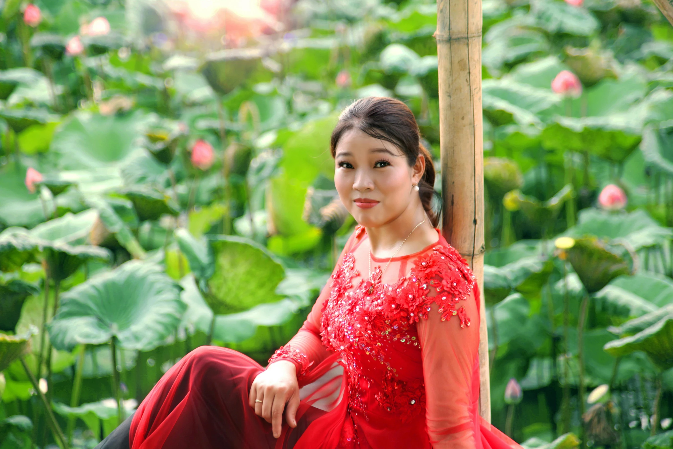 a woman sitting on a wooden post in the middle of a field