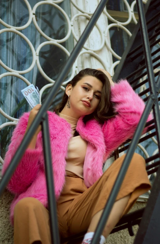 woman sitting on stairs wearing bright pink fur coat