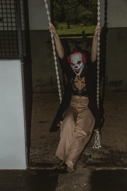 a creepy clown is sitting in a swing