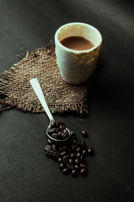 a coffee mug sits on the table next to some beans