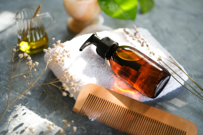 a bottle with a lotion pump is sitting on some towels next to a comb