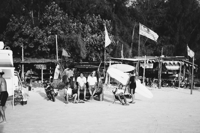 black and white po of surfers on beach with their boards