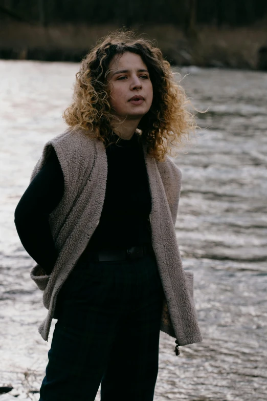 a woman standing on the edge of a lake near water