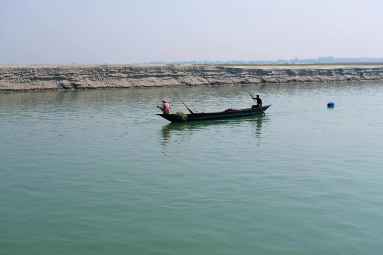 two people paddling in a boat on a calm lake