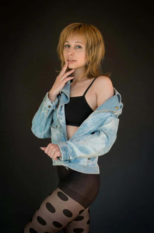 a person in tights posing with a jean jacket on