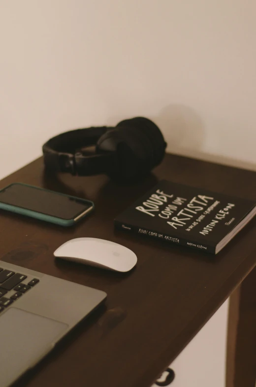 a laptop, headphones and an open book on a table
