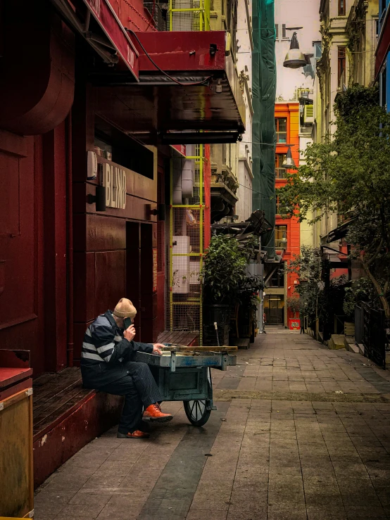 a man sitting on a sidewalk looking down the street