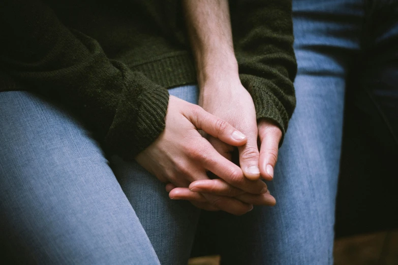 a person sitting down holding their hand on a chair