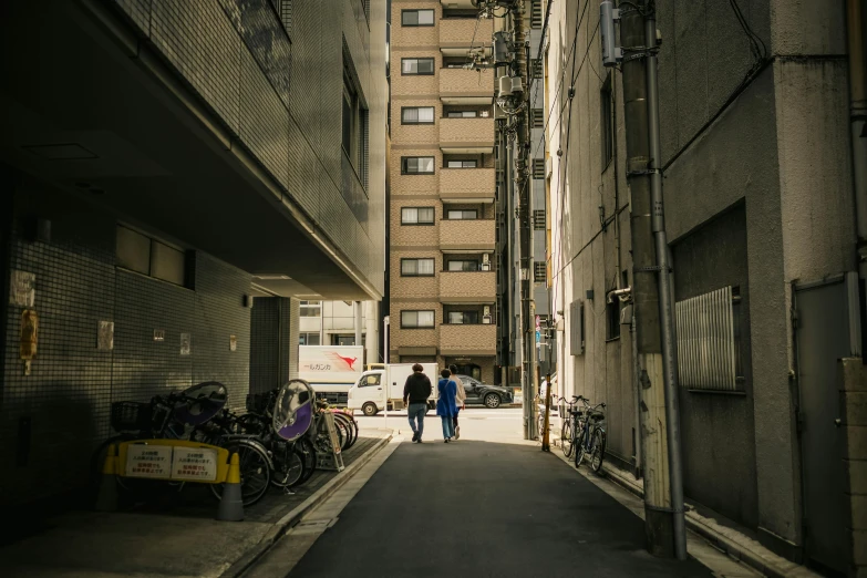 two people walking in the middle of a narrow alley way