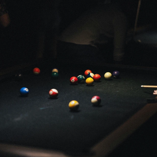 man standing by pool tables in dark room with billiard's table