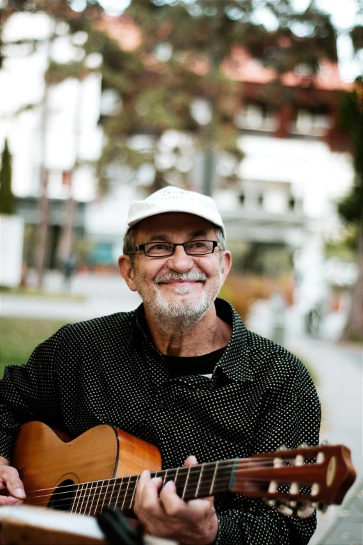 a smiling man with glasses holding a wooden guitar