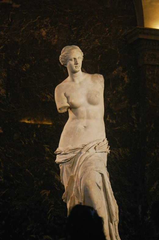 a stone statue of a  woman standing near bushes