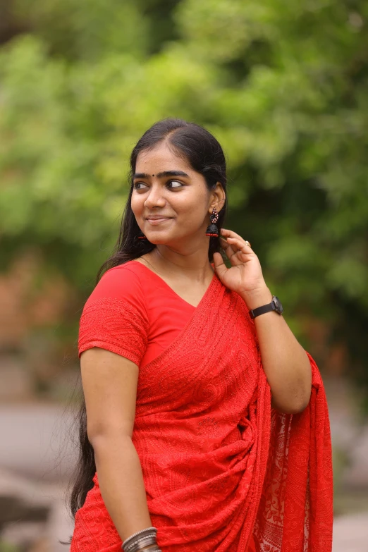 a woman smiles and poses in front of some trees