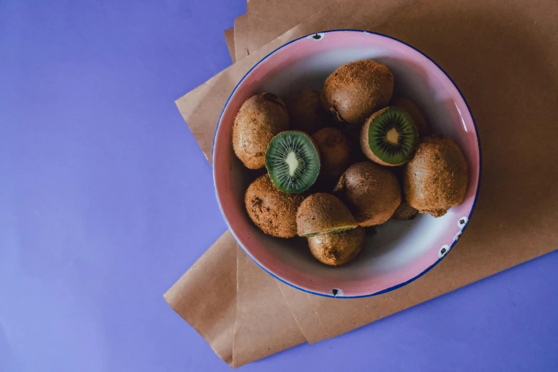 a bowl filled with kiwi fruit sitting on top of a blue table