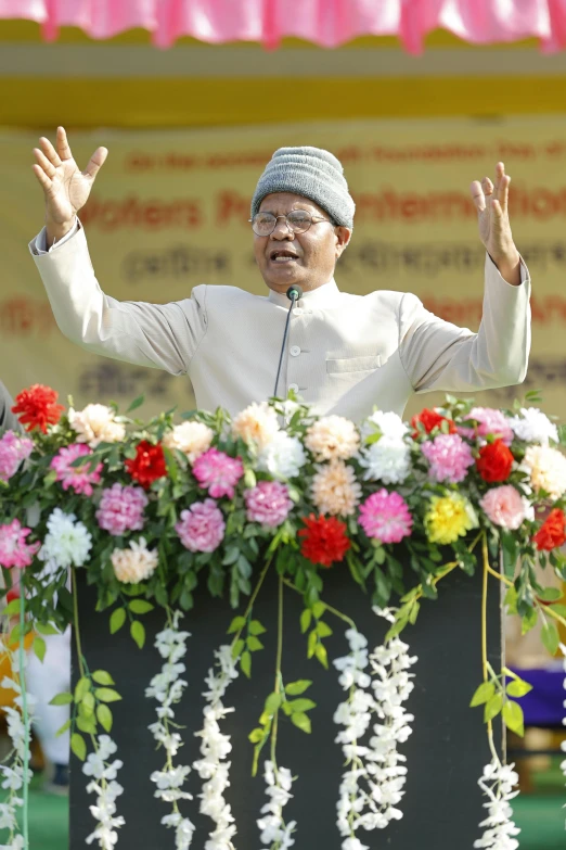 an older person standing at a podium with a hand raised