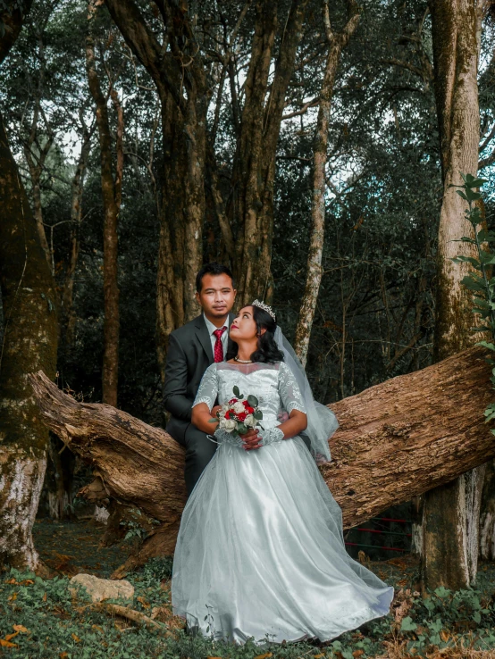 a newlywed couple pose for their wedding pograph in the woods