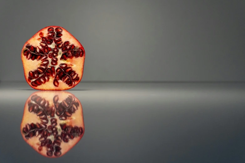 a pomegranate sitting on top of a reflective surface