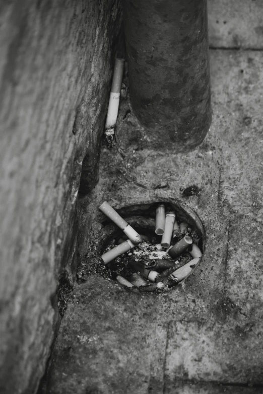 a small  in the ground with cigarettes burning in it