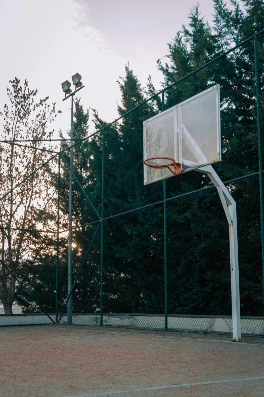 a basketball hoop and a basketball board in the evening