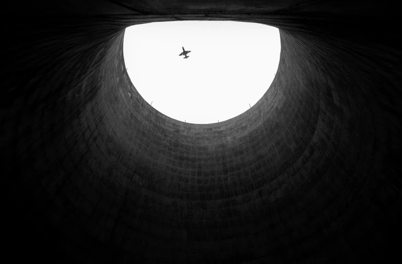 an airplane flying into a white and black circular opening