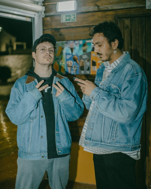 two young men standing together in front of a painting