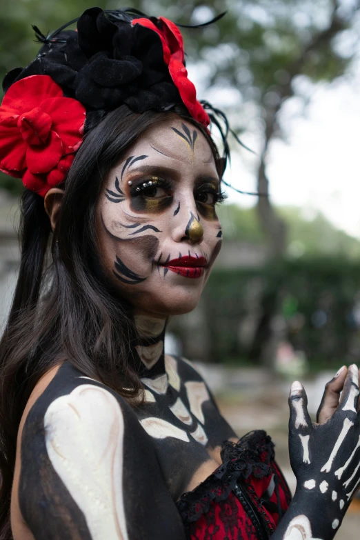 a woman in day of the dead makeup holding her hands up