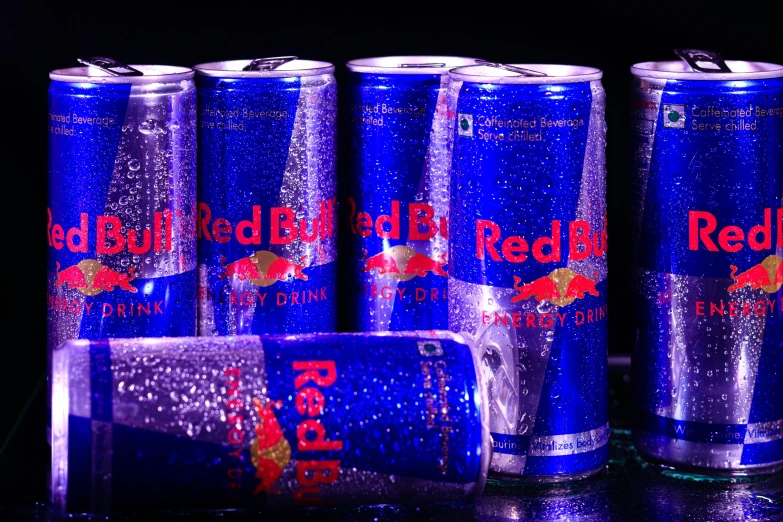 bright blue cans sitting in the dark with the red bull logo