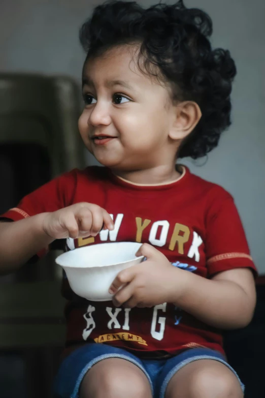 a very cute small child eating out of a bowl