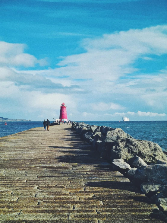 people stand on the end of a long pier next to the ocean