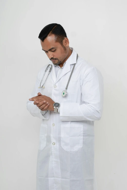 a man in a white coat stands wearing a stethoscope