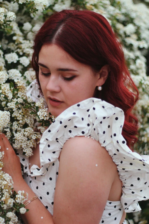 a woman holds white flowers, dressed in polka dots