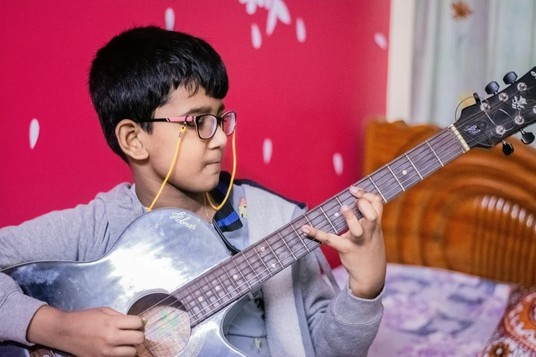 a child holding a guitar near a bed