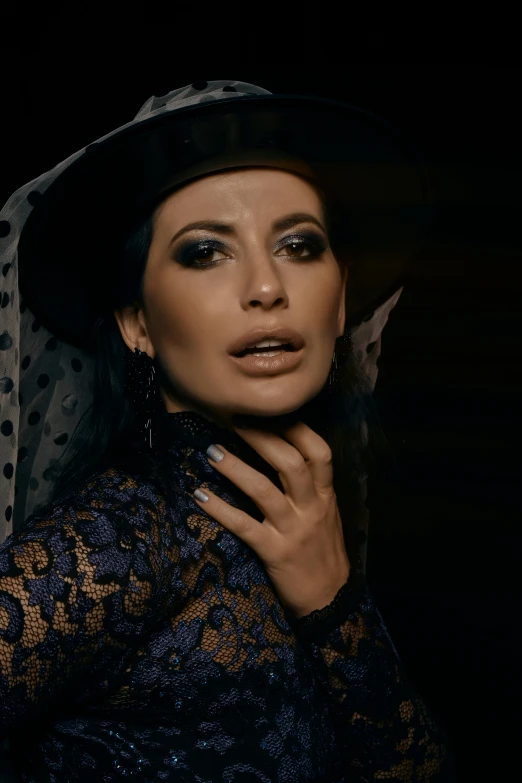 a woman with a black hat and eyeliner is posing for a portrait