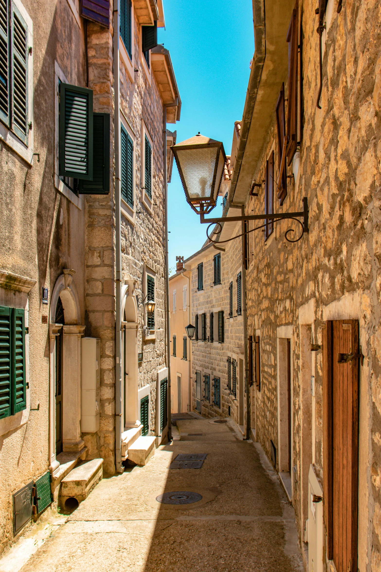 a narrow street with a lamp post and stone buildings on either side