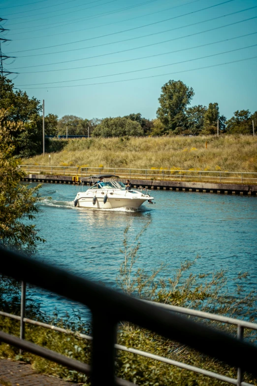 small boats pass by in the water by a railroad track