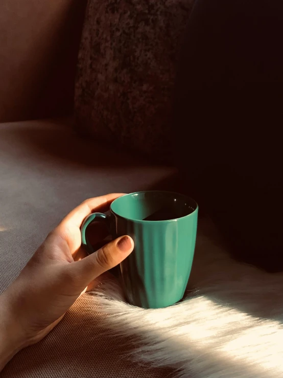 a hand holds a green cup in a dark room