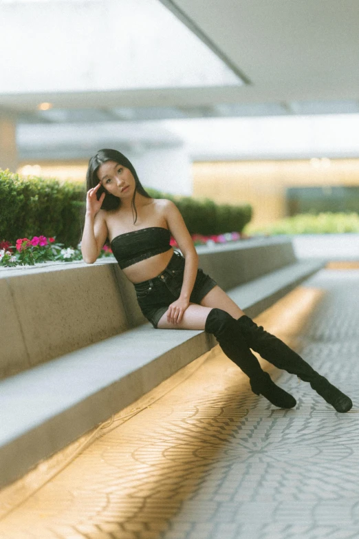 a woman in short skirt and knee high boots is sitting on a ledge