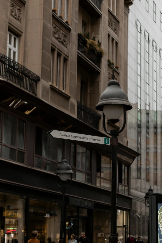 an old european streetlight with a green cross sign in the middle