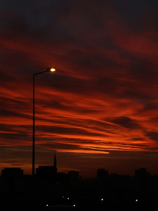 the setting sun behind clouds that cover a cityscape