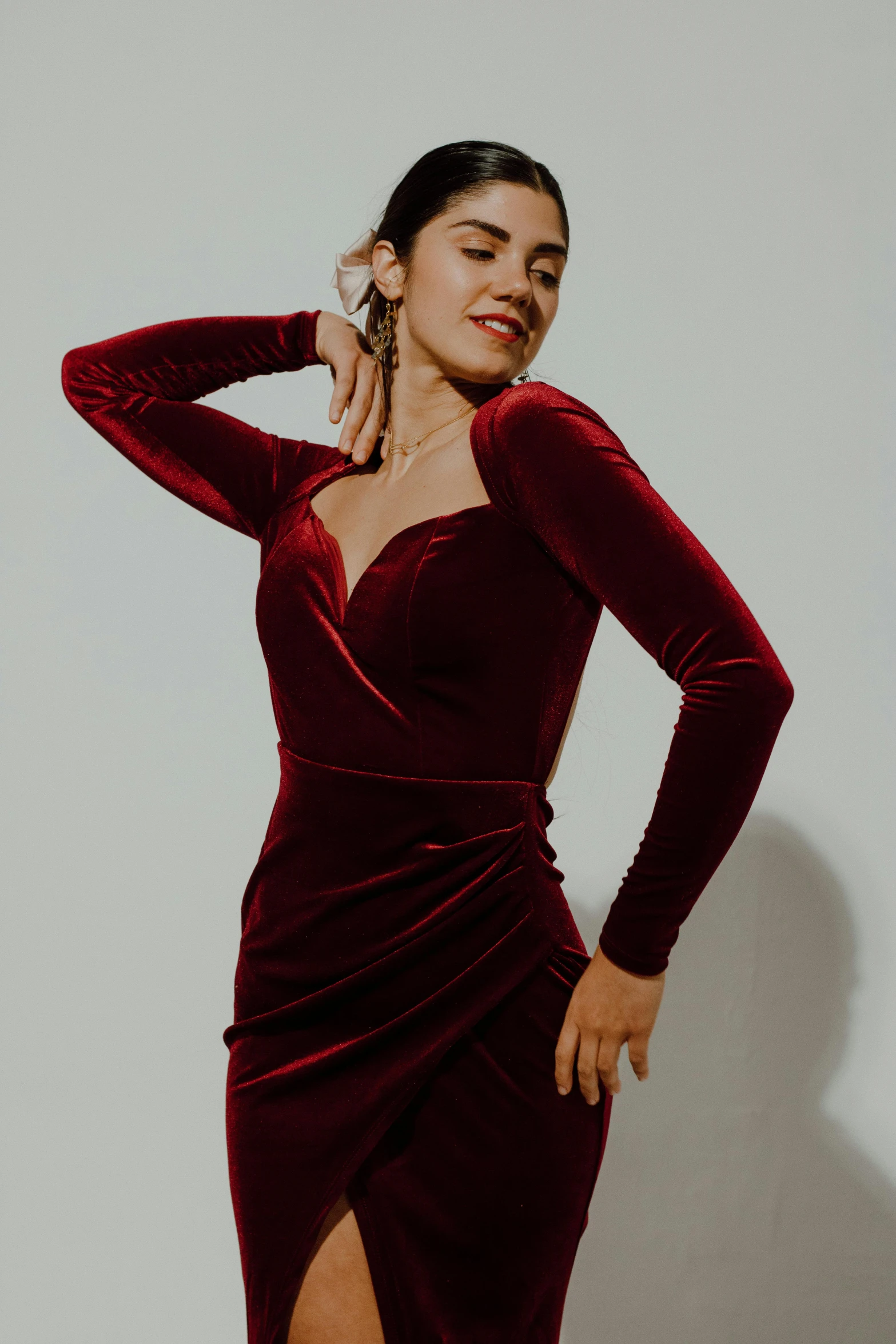 a model wears a velvet red dress by a white background