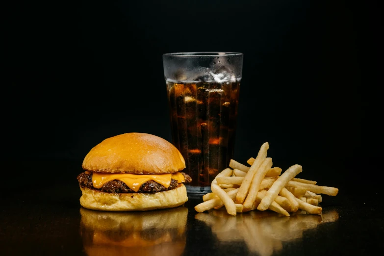 a hamburger and fries on a table next to a glass of soda