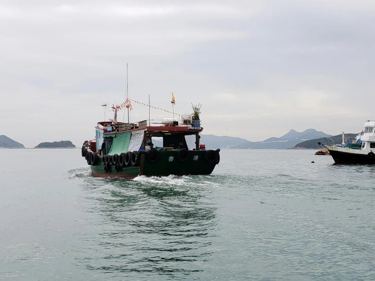 two tug boats traveling in the water with some mountains and water