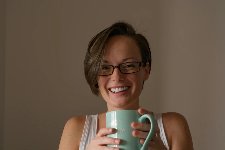 the woman smiles while holding her coffee cup