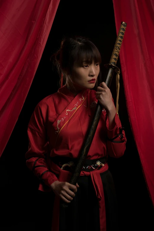 a woman in an oriental dress poses with a sword