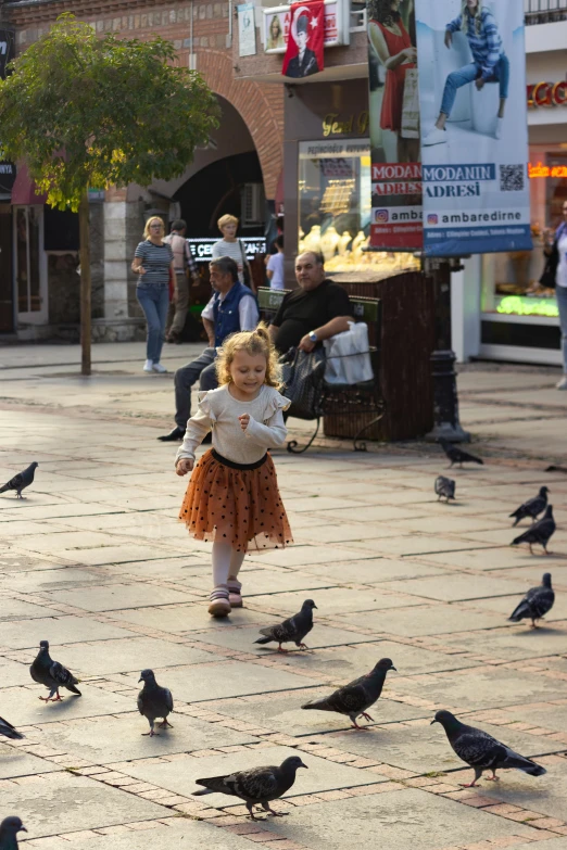 a little girl running in front of birds