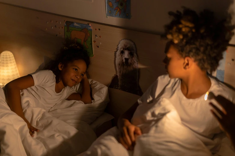 two girls lying in beds and one girl has her hand up to the other girl