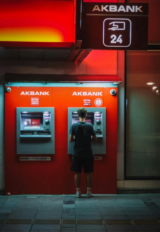 two people standing outside a machine that is giving their money