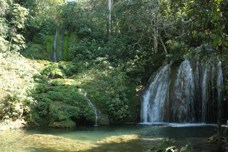 several people are standing near a waterfall