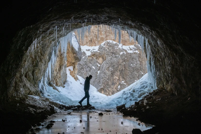two people walking in a cave, with icicles hanging on the walls